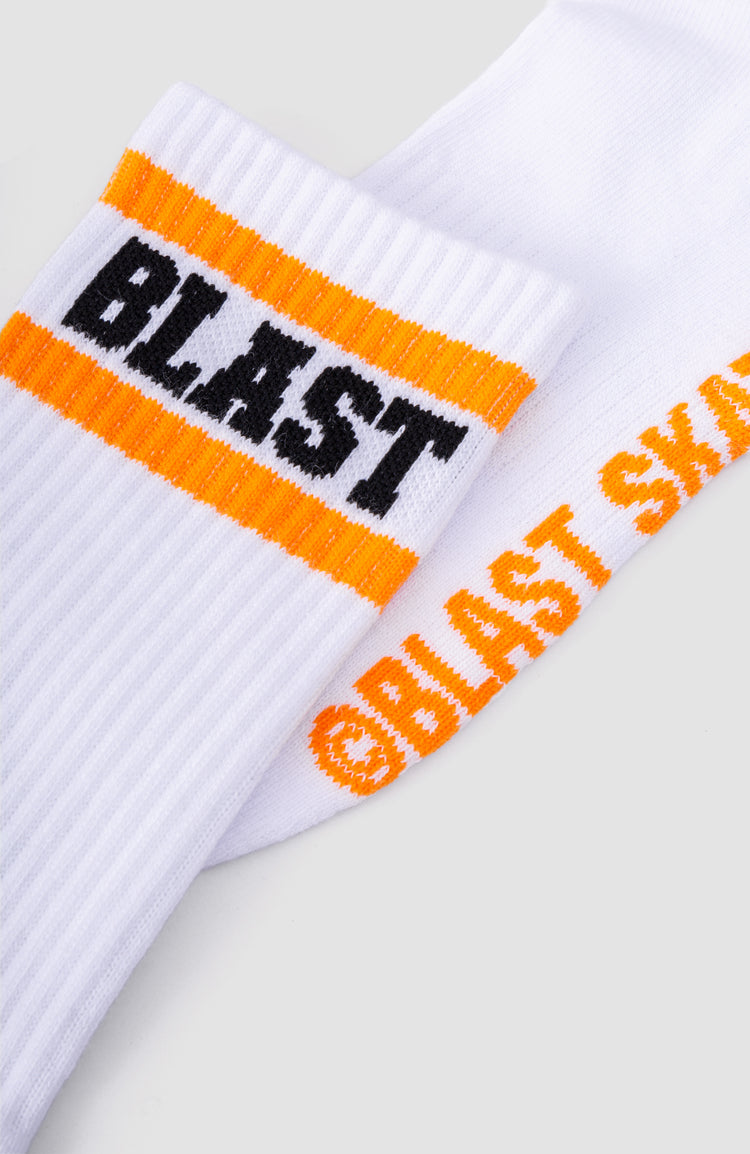 nahaufnahme von weißen Sportsocken mit schwarzem "BLAST" schriftzug und orangenen highlights.