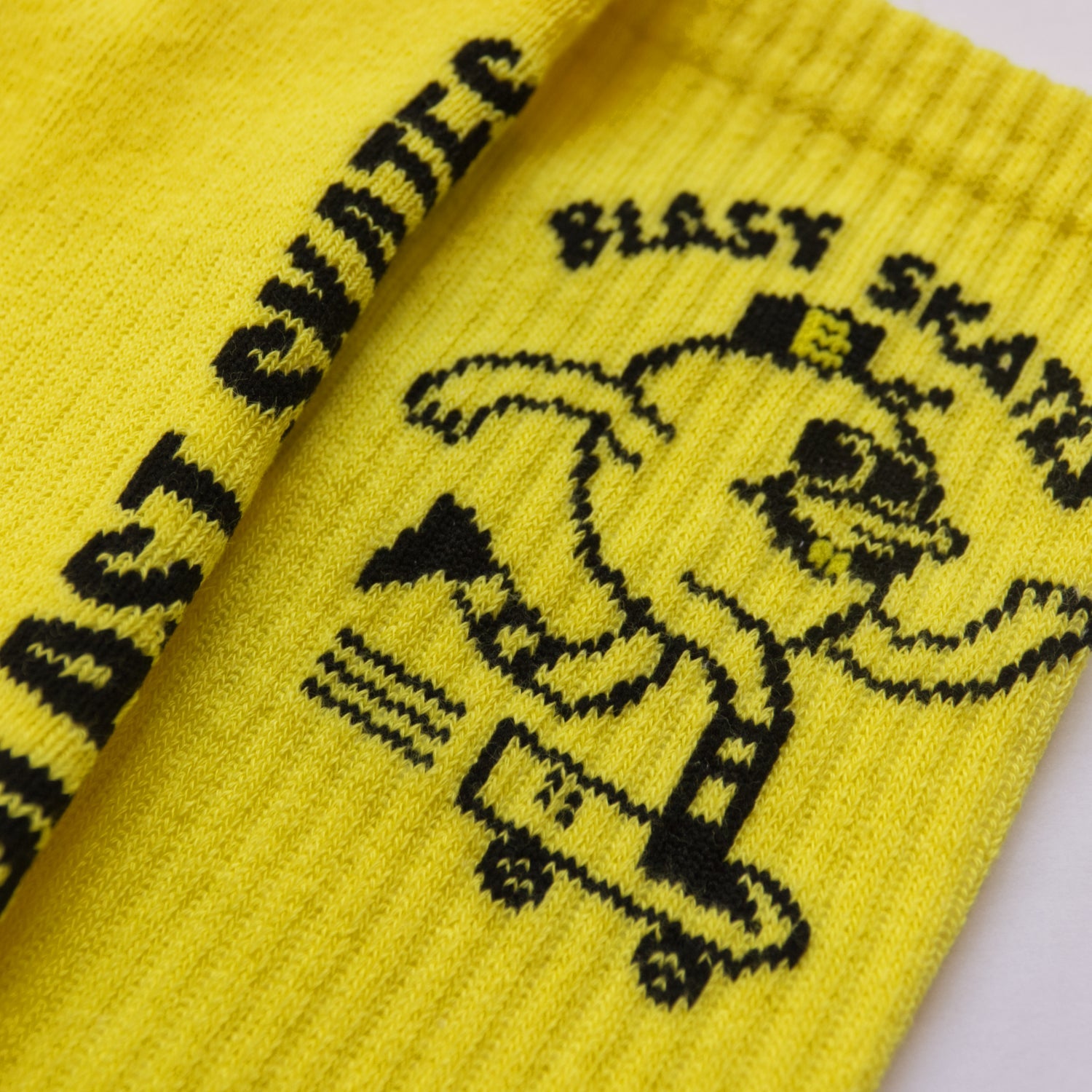 Nahaufnahme von einem schwarzen Logo, dass in eine gelbe Socke eingestrickt wurde