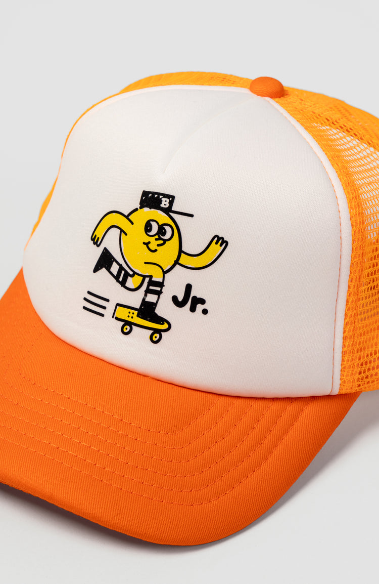 nahaufnahme von der Vorderseite einer Trucker cap in Kindergröße. auf der cap ist ein kleines gelbes Maskottchen abgebildet, das gerade skateboard fährt.