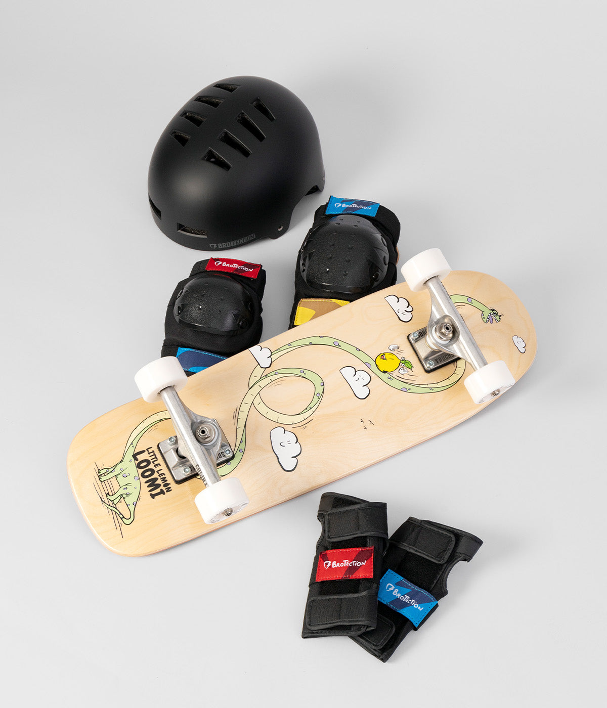 foto von einem starter skateboard set für kinder. man sieht je einen Knie- und Ellbogen-Schoner, einen Helm, ein Kinderskateboard mitt Dino-Design und 2 Handgelenkschoner